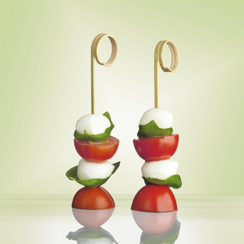 Zwei PAPSTAR 100 Fingerfood-Picker „pure“ von PAPSTAR GmbH aus hochwertigem Kunststoff halten Mozzarellakugeln, Basilikum und Kirschtomaten, dekorativ vor sanftem Grün – ideal für Partys und Events.