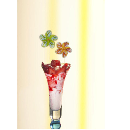 In einem hohen Glas befindet sich ein weiß-rotes Schichtdessert, garniert mit Erdbeeren und dekoriert mit PAPSTAR 50 Deko-Pickern „Windmühle“ der PAPSTAR GmbH als farbenfrohes Party-Accessoire vor hellem Hintergrund.