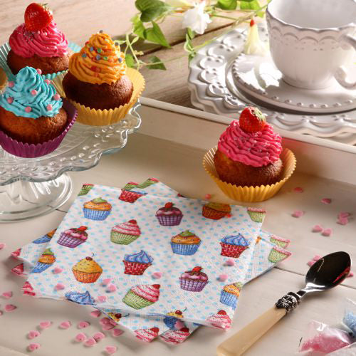 Ein Tisch ist gedeckt mit Cupcakes auf einem Glasständer, einem Teller, Löffel, weißer Teetasse und Untertasse, rosa herzförmigen Streuseln und bunten PAPSTAR 20 Servietten 33x33cm 3-lagig 1/4-Falz Design Set 5 von PAPSTAR GmbH.