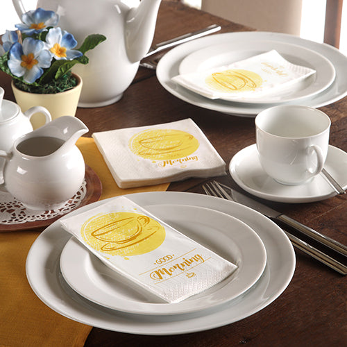 Ein ordentlich gedeckter Tisch mit weißem Geschirr, einer Teekanne, blauen Blumen und 3-lagigen PAPSTAR-Servietten (33 x 33 cm) der PAPSTAR GmbH mit einer gelben Kaffeetasse und dem Schriftzug "Morning".