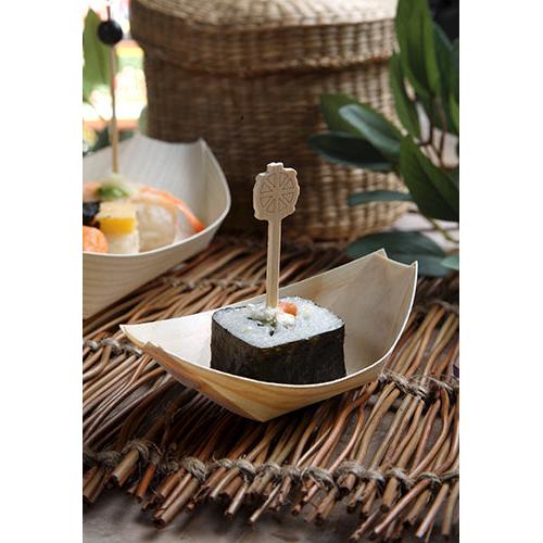 Ein Stück Sushi, in Seetang gewickelt und mit einem Holzspieß gehalten, wird auf einer PAPSTAR 50 Fingerfood-Schale Holz „pure“ Schiffchen der PAPSTAR GmbH serviert, präsentiert auf einer gewebten Matte mit Blättern und Weidenkörben im Hintergrund.