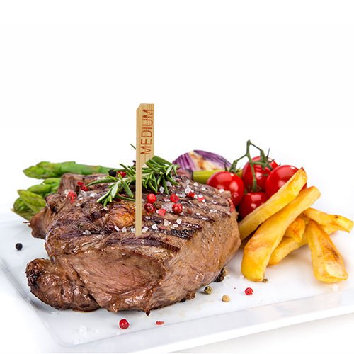 A grilled steak labeled "medium" with the PAPSTAR 250 steak marker 9 cm from PAPSTAR GmbH is served on a white plate with French fries, asparagus, cherry tomatoes, red onions, and herbs – perfect for the professional restaurant kitchen.