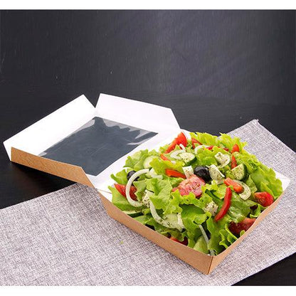 The PAPSTAR 25 gourmet boxes made of cardboard with a PLA window from PAPSTAR GmbH present fresh salad with tomatoes, onions, olives, and herbs stylishly on gray fabric against a dark background.