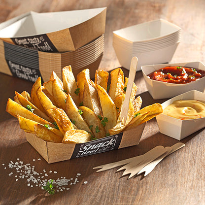 A PAPSTAR 50 French fries tray "pure" (3.5 x 7 cm) from PAPSTAR GmbH holds thick-cut potato wedges with parsley, along with two dip sauces, additional forks, empty trays, and salt on the wooden table for an environmentally friendly touch.