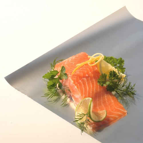 Zwei rohe Lachsfilets liegen auf einem Blatt Starpak Alufolie lose von Starpak, garniert mit frischem Dill, Petersilie, Zitronenschale und Limettenscheiben, vor einem schlichten hellen Hintergrund.