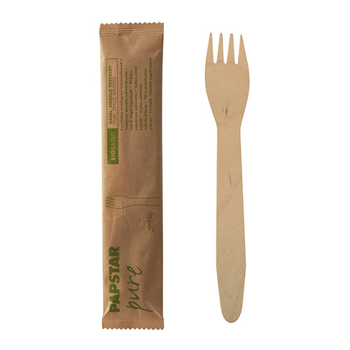 Eine Holzgabel der PAPSTAR GmbH wird neben ihrer braunen Papierhülle mit der Aufschrift „PAPSTAR pure“ in einer umweltfreundlichen Verpackung mit Text und kleiner Gabelabbildung präsentiert. Produkt: PAPSTAR 50 Gabeln, Holz „pure“ 15,5 cm, einzeln im Papierbeutel (50 Stück).