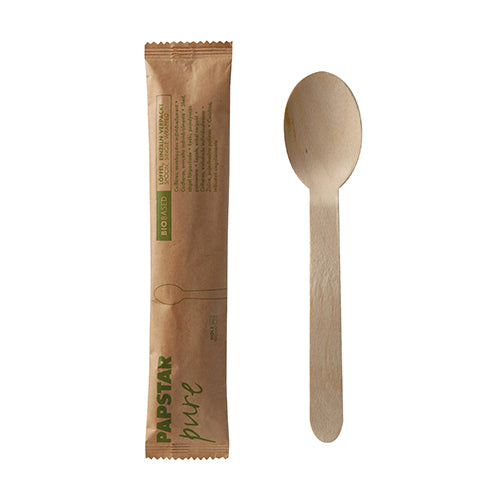 Ein PAPSTAR 50 Löffel, Holz „pure“ 16 cm einzeln verpackt im Papierbeutel von PAPSTAR GmbH ist neben seiner braunen Verpackung mit grün-brauner Beschriftung und schlichter Illustration auf weißem Hintergrund abgebildet.