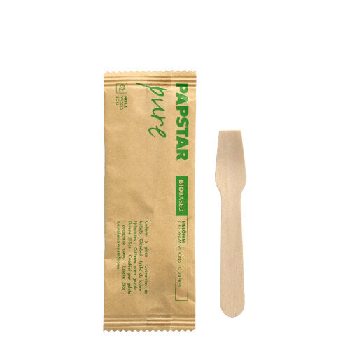 Ein hygienischer Holz-Eislöffel der PAPSTAR GmbH liegt in seiner braunen „pure“-Verpackung aus Papier mit grünen und schwarzen Details. Der 9,4 cm große Löffel ist einzeln verpackt, 50 Stück befinden sich in einer umweltfreundlichen Packung.