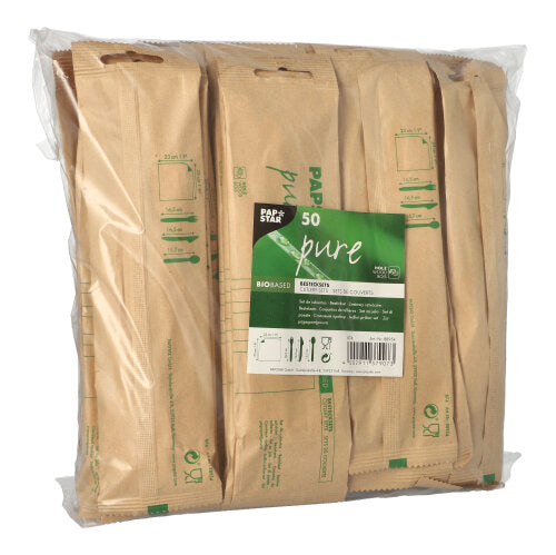Eine Klarsichtverpackung der PAPSTAR GmbH enthält 50 „pure“-Holzbestecksets mit Servietten, jedes einzeln in biologisch abbaubares braunes Papier eingewickelt und mit der grünen Aufschrift „pure“ versehen.
