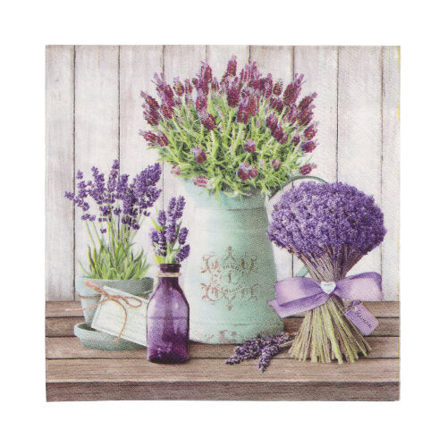 Ein Lavendelbouquet, eine lila Flasche, ein weißer Krug mit Lavendel und eine grüne Teetasse stehen auf Holz neben PAPSTAR GmbH 20 Servietten 33x33cm 3-lagig 1/4-Falz Design Set 3 vor einer weißen Holzwand.