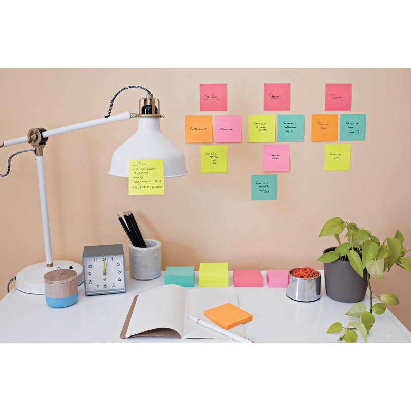 A desk with a white lamp, pencils in a cup, a clock, an open notebook, and a plant. The Post-it® Super Sticky Notes (47.6 mm x 47.6 mm) from 3M are arranged with handwritten tasks on the beige wall above the desk.