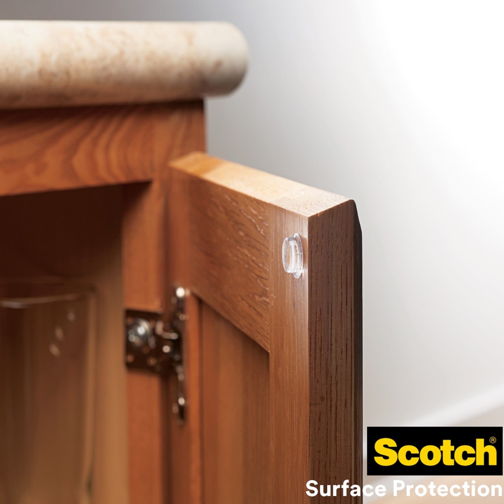 Ein Scotch® Stoßabsorbierender Elastikpuffer, selbsthaftend, transparent von 3M Deutschland GmbH ist am Rand einer Holztür angebracht, um Schäden zu verhindern. Das Scotch Surface Protection Logo ist unten rechts sichtbar.