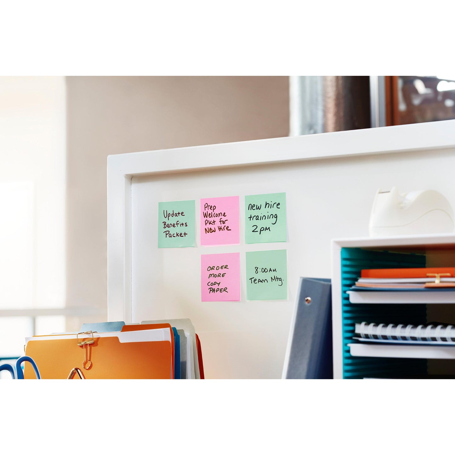 A white office divider is adorned with six colorful Post-it® notes (76 mm x 127 mm, 100 sheets/block, 6 blocks/pack, 100% PEFC, 3M Deutschland GmbH) listing tasks such as updating performance packages and team meetings. Supplies and binders are nearby.