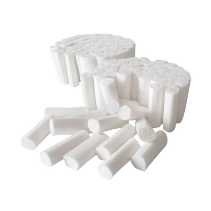 Two stacks of AMPri MED-COMFORT Dental cotton rolls, cylindrical and white, are prominently displayed, several of them scattered in the foreground. These disposable sponges are manufactured by AMPri Handelsgesellschaft mbH from chlorine-free bleached cotton and are neatly arranged against a plain white background.