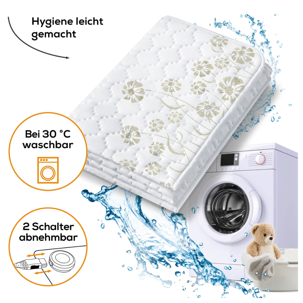 Das Bild zeigt ein Beurer Doppel-Wärmeunterbett UB 68 XXL | Packung (1 Stück) der Beurer GmbH, geschmückt mit floralen Motiven und einer gesteppten Matratzenauflage. Der Text weist darauf hin, dass es pflegeleicht, bei 30°C waschbar und mit zwei separat regelbaren Wärmezonen ausgestattet ist. Eine Waschmaschine mit Wasserspritzern und ein Teddybär sind ebenfalls Teil der visuellen Präsentation.