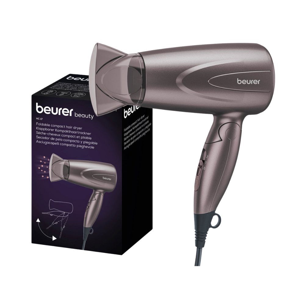 Image of a foldable compact hairdryer Beurer HC 17 next to its packaging. The hairdryer from Beurer GmbH is gray and has a foldable handle, highlighting its practical design as a compact hairdryer. The packaging shows the product image and description, emphasizing its impressive performance capabilities.