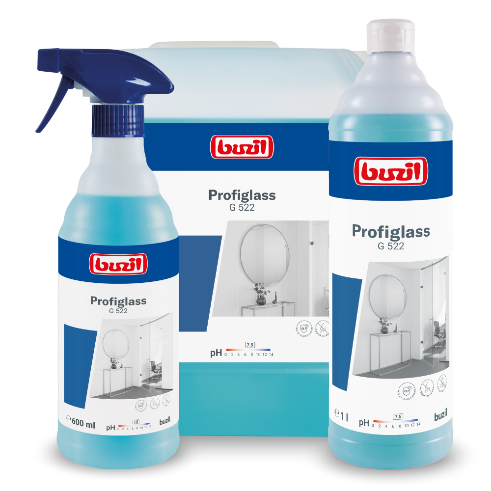 The image shows three containers with the ready-to-use glass and surface cleaner Buzil Profiglass G 522 from BUZIL-WERK Wagner GmbH & Co. KG, on the left a spray bottle, behind it a gallon jug, and on the right a tall bottle. Each container is labeled with a blue label highlighting the cleaner's ability to create streak-free shine and remove greasy residues from glass surfaces.
