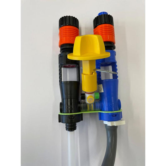 Zwei Dosierinjektoren, ein schwarzer und ein blauer mit orangefarbener Spitze, sind durch ein grünes Band und eine gelbe Kappe mit einem unteren grauen Schlauch verbunden. Teil des QuattroSelect Manifold Air Gap Oxivir Excel JFill Systems von Diversey Deutschland GmbH & Co. OHG.