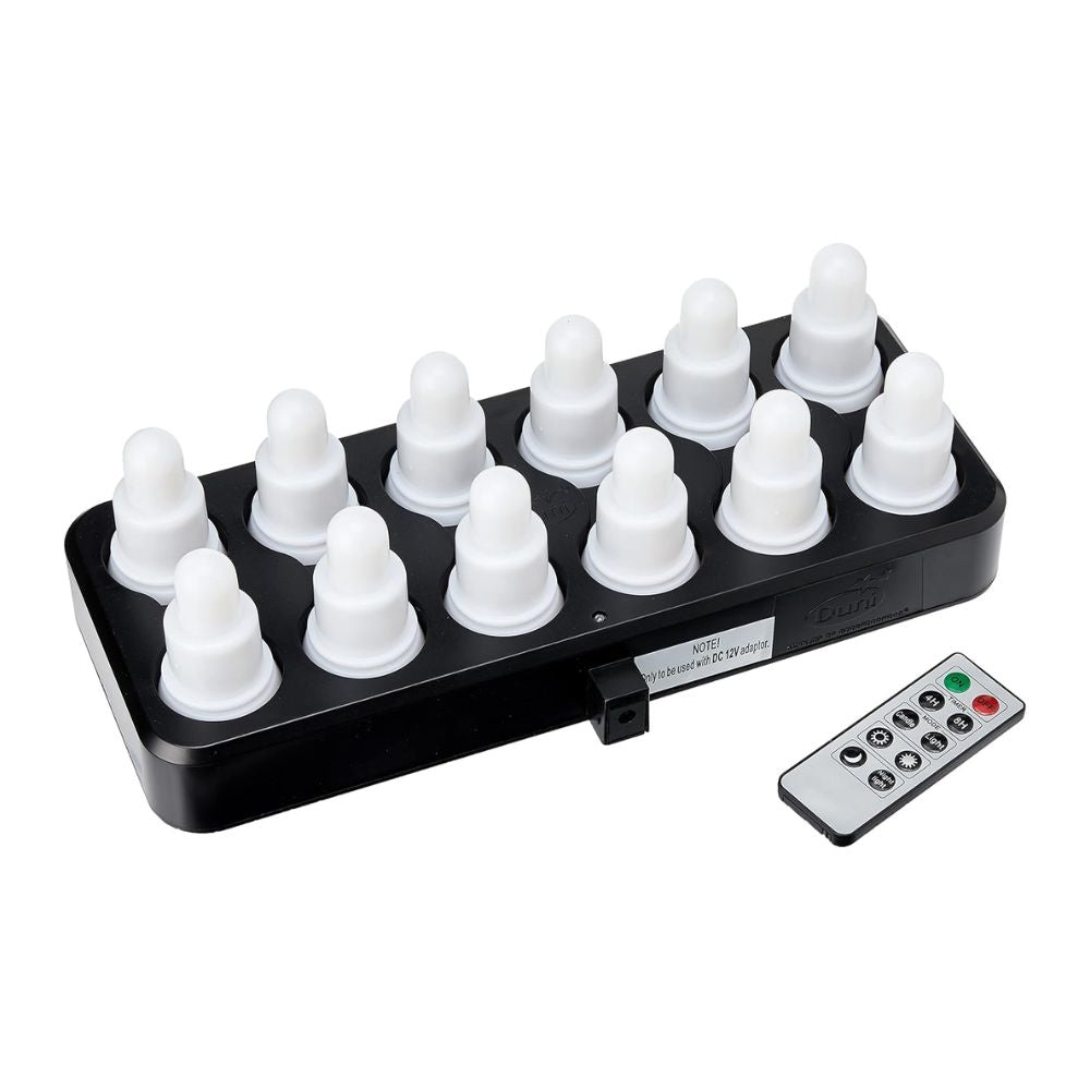 A black charging station holds twelve white, onion-shaped lights from the Duni GmbH LED Set, Warm White & Multicolor - 12 Piece Color Changing Lights. Next to it is a rectangular remote control for easy control of color and mode.