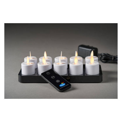 A Duni GmbH LED Moving Flame (38x36 mm, pack of 1 piece) with a realistic flickering effect is shown on a black charging station, with a matching remote control and power supply to the right.