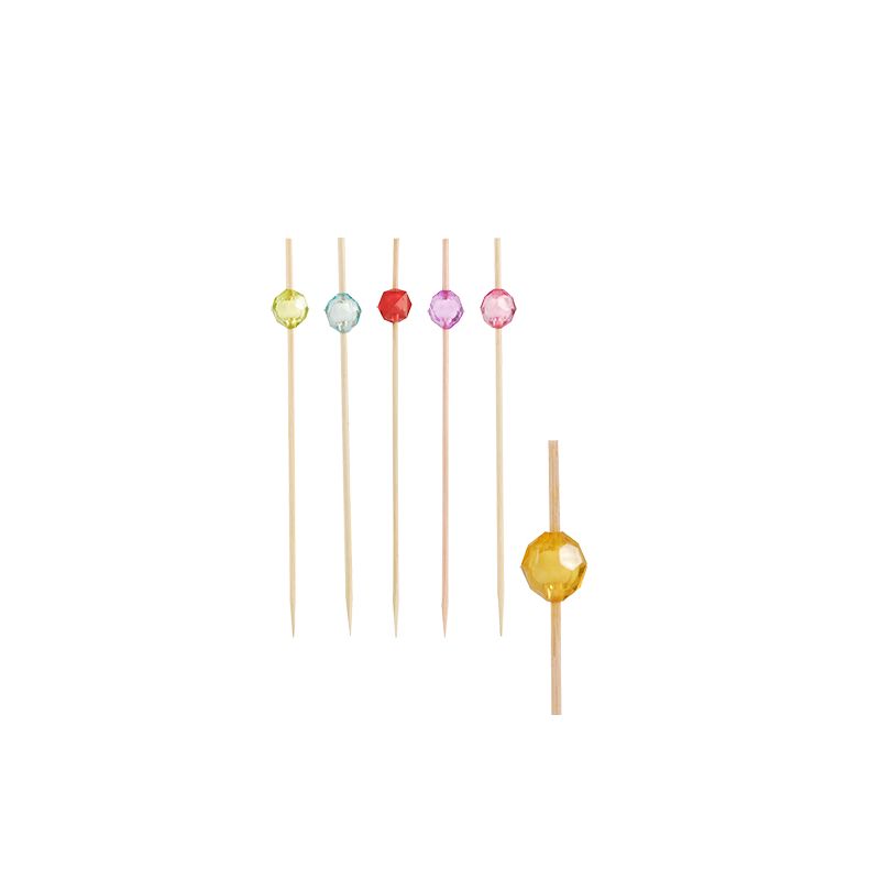 Five PAPSTAR finger food skewers, each adorned with a striking color bead in green, yellow, red, pink, and blue, are arranged vertically. An additional skewer with an amber bead lies horizontally to the right. These bamboo skewers are perfect for elegantly serving finger food and are designed as sustainable disposable products by PAPSTAR GmbH.