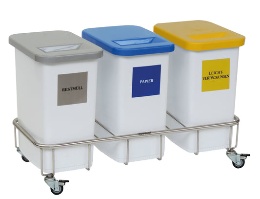 Der Novocal Wertstoffsammler Fahrgestell, Dreifachsammler aus Edelstahl bietet drei Kunststoffbehälter mit farbigen Deckeln (Grau: Restmüll, Blau: Papier, Gelb: Leichtverpackungen), jeweils mit Beschriftung und Einwurfschlitz.