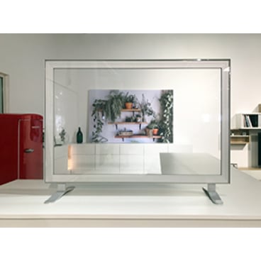 Eine Novocal Hygieneschutzwand gerade ohne Durchreiche (transparent, 1.200 x 600 mm) mit Metallkanten steht auf einer weißen Fläche; dahinter ein Wandregal mit Pflanzen, links ein roter Kühlschrank.