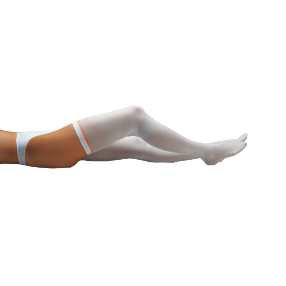 A person lying down, stretching their legs in the air, is wearing Holthaus Medikur® thrombosis prophylaxis stockings with orange stripes at the top edge and dark underwear. The background is plain white.