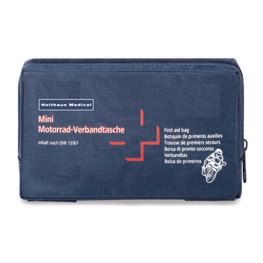 Eine dunkelblaue Erste-Hilfe-Tasche mit dem Aufdruck „Holthaus Mini Motorrad Verbandtasche DIN 13 16“ in weißer und roter Schrift. Die Tasche zeigt außerdem eine kleine Motorradabbildung und enthält mehrsprachige Etiketten, die darauf hinweisen, dass es sich um eine Erste-Hilfe-Ausrüstung nach DIN 13167 handelt, hergestellt von Holthaus Medical GmbH & Co. KG.