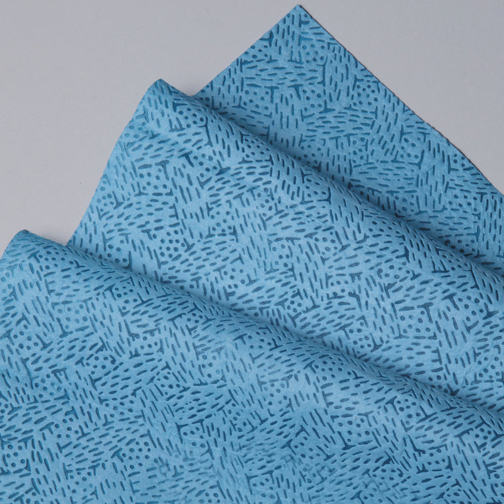 Eine Nahaufnahme der blauen Kimtech® Prozeßwischtücher Großrolle der Kimberly-Clark GmbH, die ein geometrisches Muster zeigt. Eine Rolle mit 500 Blatt liegt auf einer glatten, hellgrauen Oberfläche - ideal für die industrielle Reinigung.