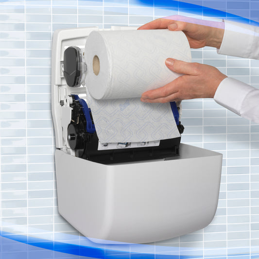 Eine Person lädt eine große Rolle Papierhandtücher in den weißen Aquarius™ Slimroll™ Rollenhandtuchspender der Kimberly-Clark GmbH, der an einer Wand mit einem blau-weißen Kachelmuster im Hintergrund angebracht ist.