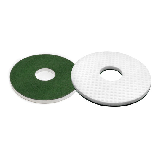 Abgebildet sind zwei runde Bodenpads: ein Arcora Melamin Rundpad, komprimiert gepresst mit einem grünen Padrücken und einem strukturierten, gitterartigen Muster, und beide haben ein rundes Mittelloch. Marke: Arcora International GmbH.