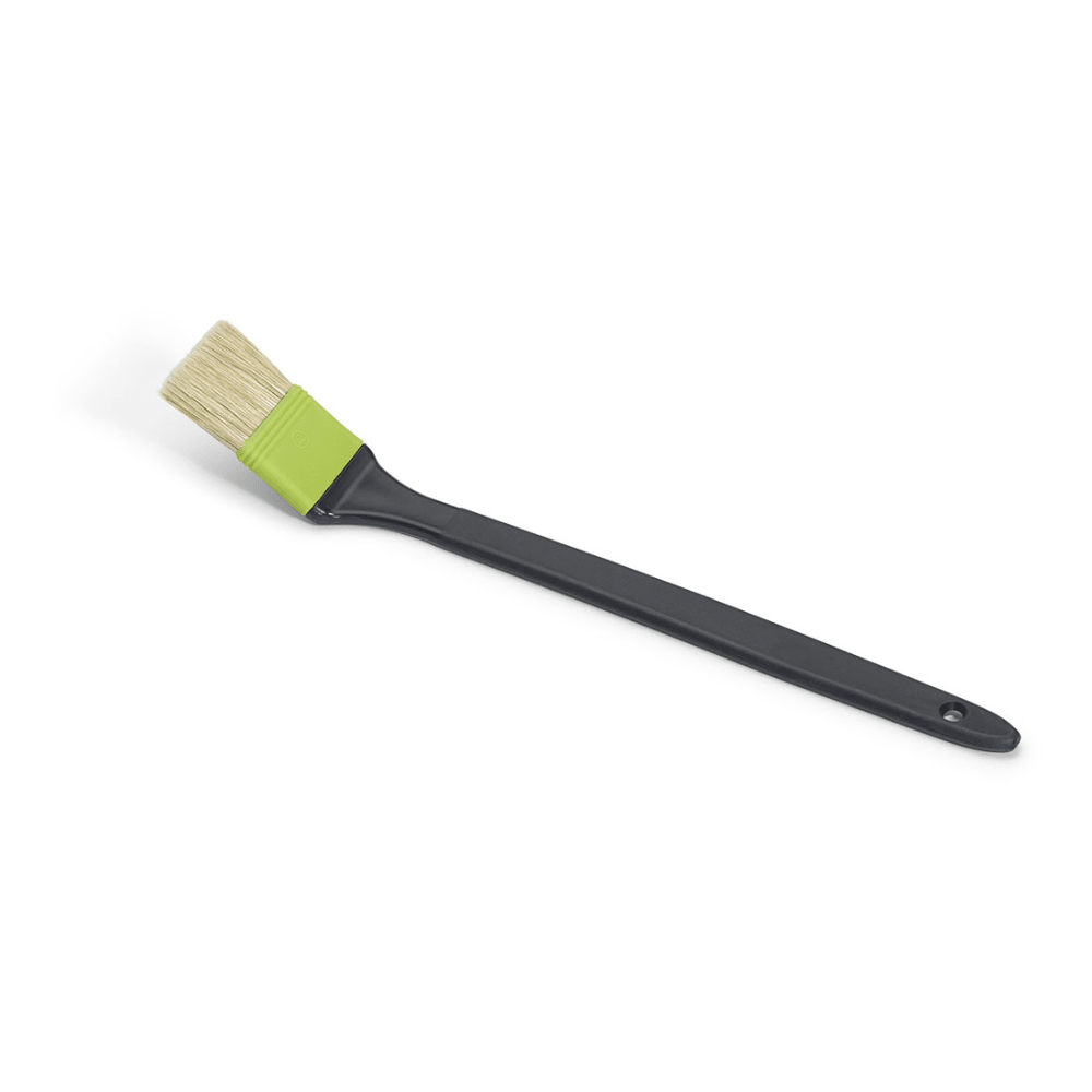 The Nölle Profi Brush industrial radiator brush with beige bristle mix and long black handle with hanging hole is ideal for water-based paints. Its bristle head is held by a green band and stylishly lies at an angle against a white background.