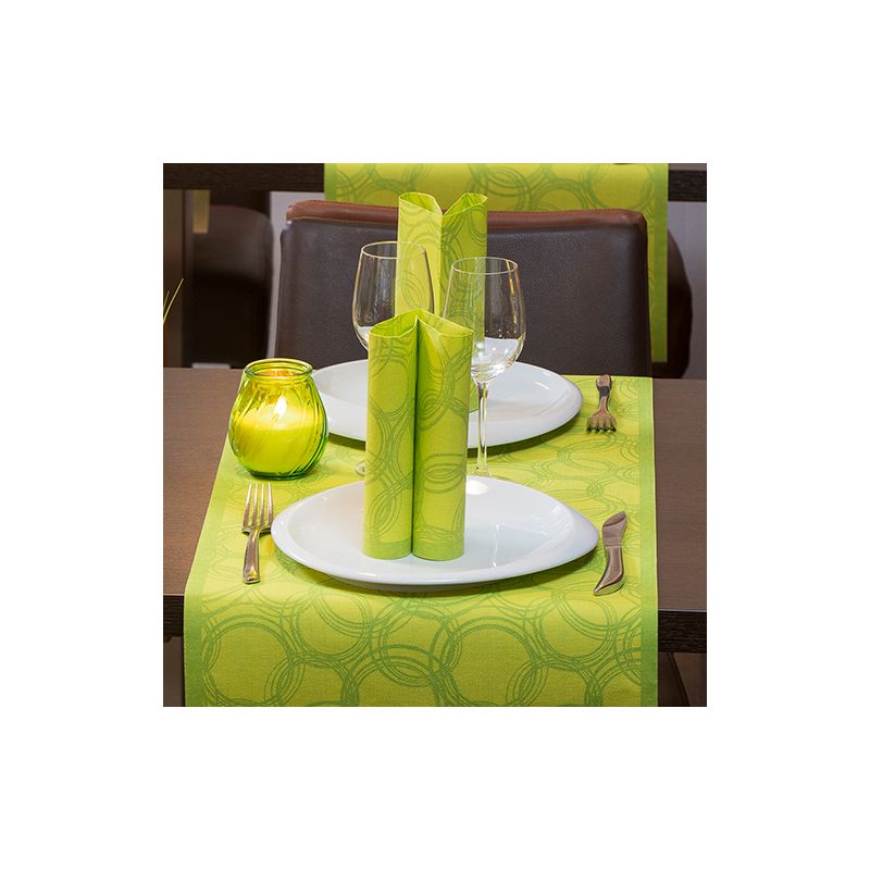 A dining table is elegantly set for two with white plates, stemware, and cutlery. Green napkins are artfully placed on the plates. A green candle holder stands on a PAPSTAR table runner fabric-like PV-Tissue Mix “ROYAL Collection” by PAPSTAR GmbH, whose circular pattern adds sophistication to the scene.