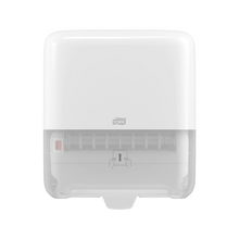 A white, wall-mounted Tork Matic® 551000 dispenser for roll towels Elevation H1 with a transparent bottom for easy level indication. The front features the TORK logo – Essity Professional Hygiene Germany GmbH, as well as a diagram showing how to pull out the roll towels.