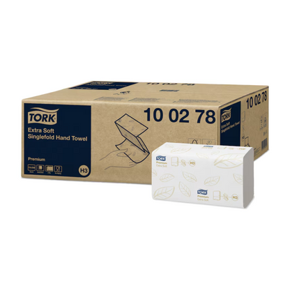 The packaging for Tork 100278 extra soft zigzag towels Premium H3 2-ply combines hygiene and elegance with its brown and white design. The larger brown box displays the product details, while the smaller white box highlights the Premium H3 towel design with green leaf motifs and the Tork logo, representing the brand TORK – Essity Professional Hygiene Germany GmbH.