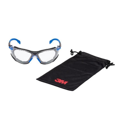 The 3M™ Solus™ Safety Glasses 1000 from 3M Deutschland GmbH with clear lenses, blue and black frame, and foam gasket is shown next to a black case with a red 3M logo.