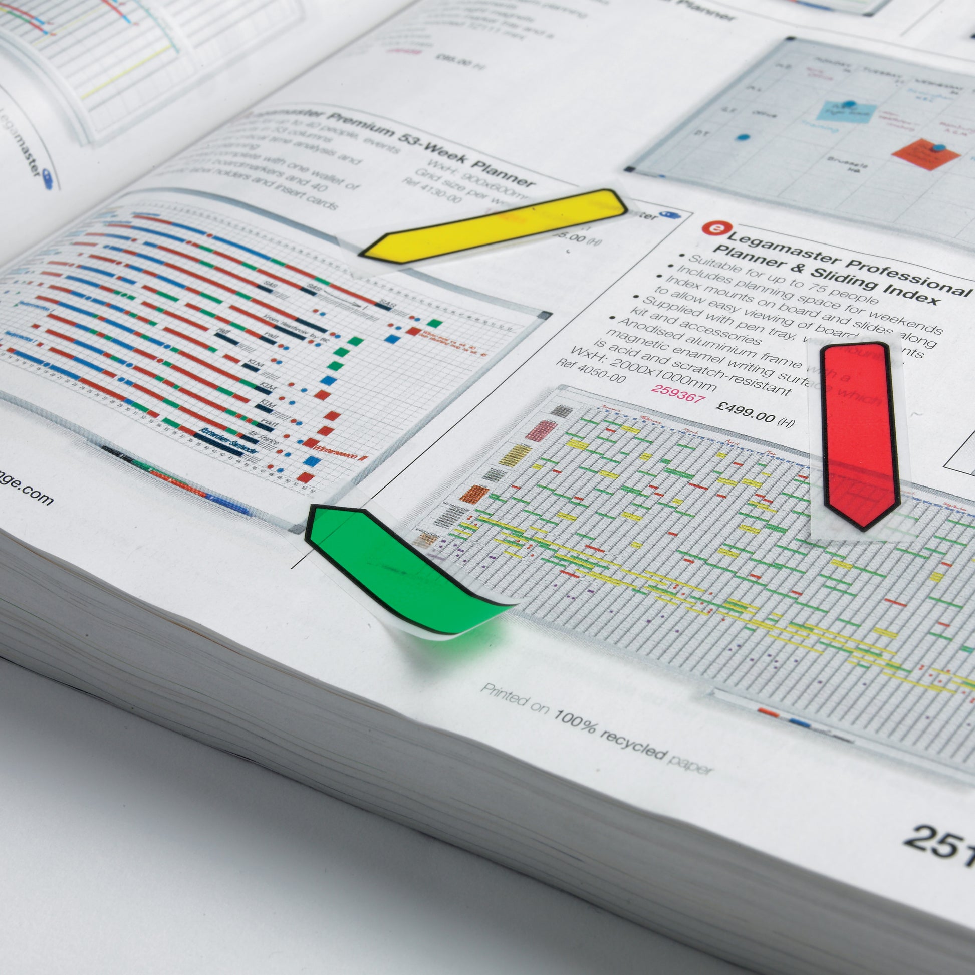 Ein aufgeschlagenes Buch zeigt Tabellen und Diagramme mit drei bunten Post-it® Index Pfeilen von 3M Deutschland GmbH-gelb, rot und grün-(11,9 mm x 43,2 mm) an verschiedenen Stellen auf den Seiten platziert.