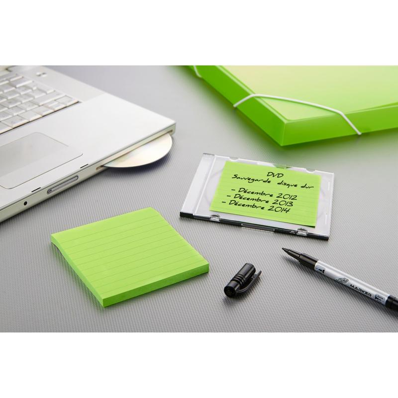 A laptop with an open drive, a green file folder, a black marker without a cap, a DVD case labeled in Spanish, and 3M Deutschland GmbH Post-it® Super Sticky Notes in large format (101 mm x 101 mm) lie on a gray surface.