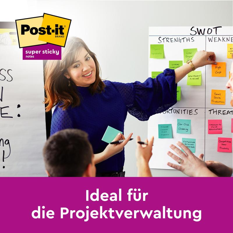 A woman in a blue blouse is leading a workshop and pointing to a SWOT analysis with colorful Post-it® Super Sticky Notes (76 mm x 76 mm, 90 sheets/block, 100% PEFC) from 3M Deutschland GmbH, while others participate.