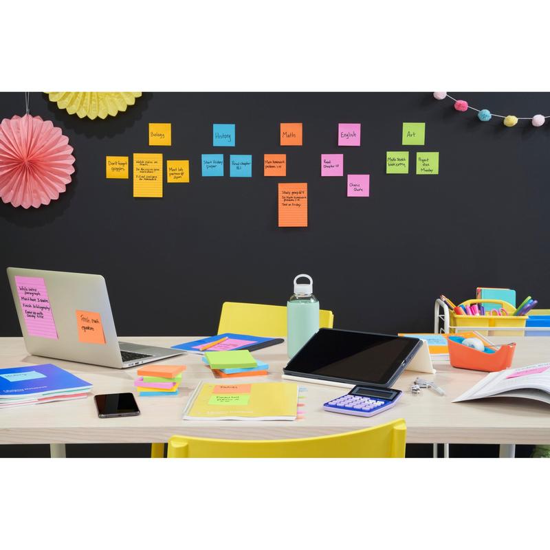 A workspace in the classroom is equipped with a laptop, tablet, notebook, calculator, phone, water bottle, and Post-it® Super Sticky Notes (76 mm x 76 mm, 90 sheets/block) from 3M Deutschland GmbH, color-coded by school subjects like biology and mathematics.