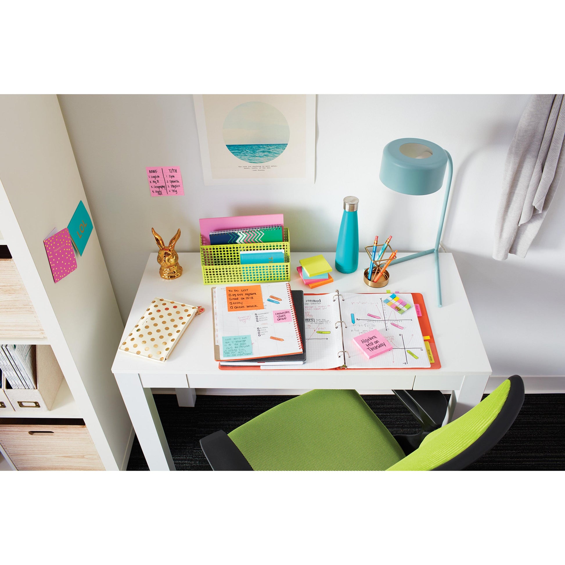 Ein weißer Schreibtisch mit einer offenen Mappe, Notizbüchern, 3M Post-it® Notizen (76x76 mm, 100 Blatt, 100% PEFC), Schreibmaterial, einer Lampe, einer Wasserflasche und Organizern. Davor steht ein grüner Stuhl; an der Wand hängen ein Bild und Post-it® Notes.