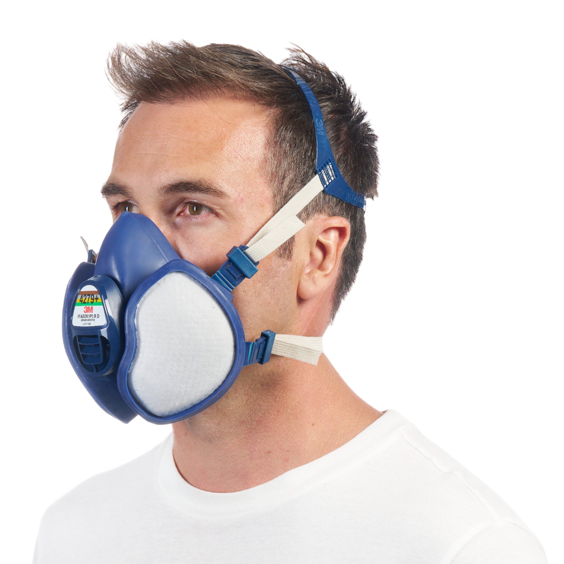 Ein Mann mit kurzen braunen Haaren und weißem Hemd ist im Profil zu sehen. Er trägt die 3M™ Atemschutzmaske mit integrierten Filtern der 3M Deutschland GmbH, die ein blaues Design und verstellbare Kopfbänder aufweist.