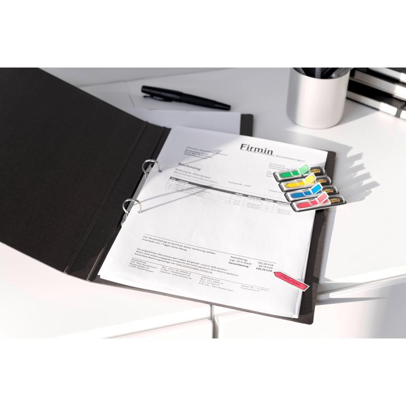 An open black folder with printed documents, colorful 3M Post-it® Index Arrows (11.9 mm x 43.2 mm, 24 adhesive strips/dispenser), and a pen on a white desk; in the background, office supplies from 3M Deutschland GmbH can be seen.