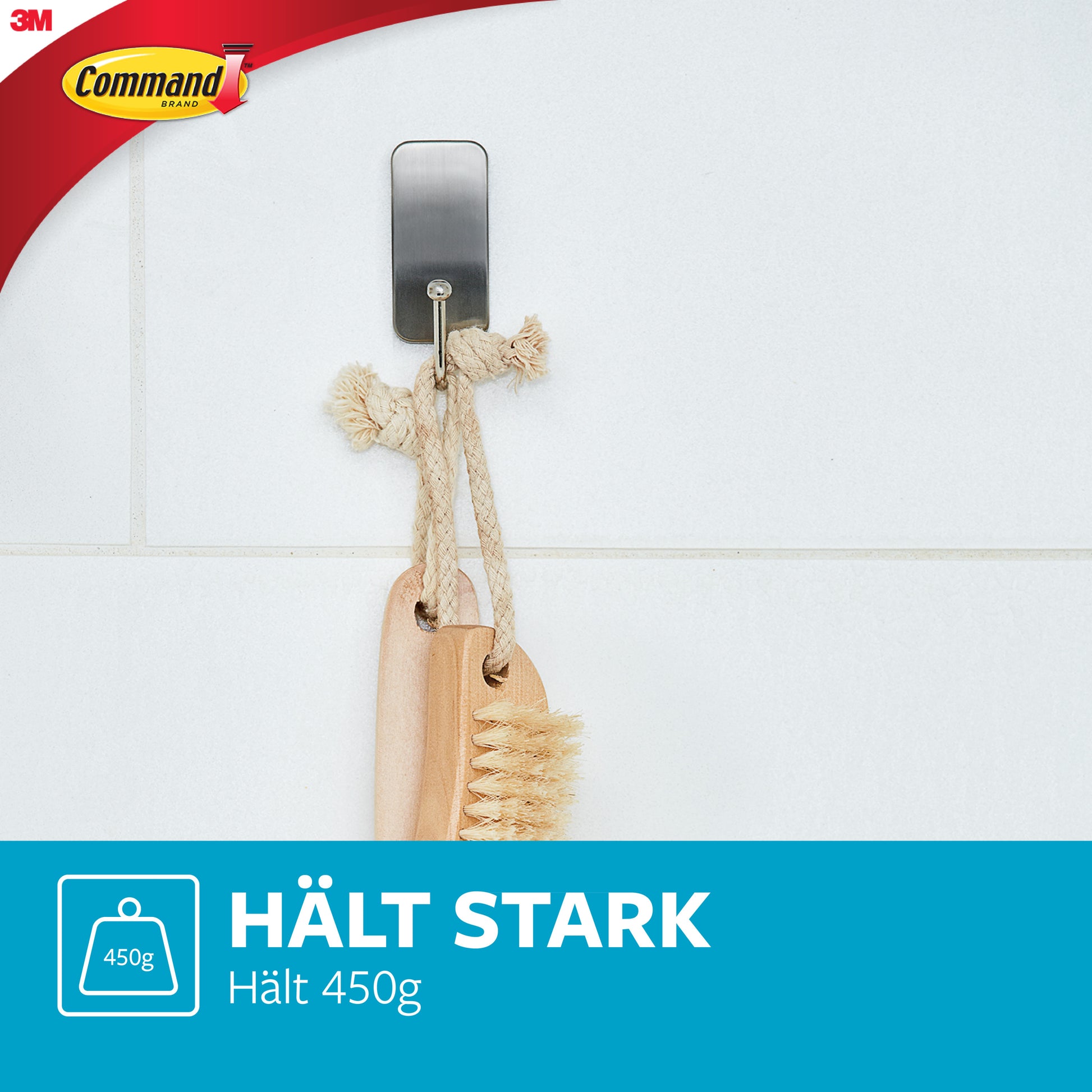 An Command™ Metall-Haken Bad, schmal, Satin Nickel von 3M Deutschland GmbH ist an weißen Fliesen angebracht. Zwei Holzbürsten mit Seilgriffen hängen daran. Text darunter: "HÄLT STARK Hält 450g.