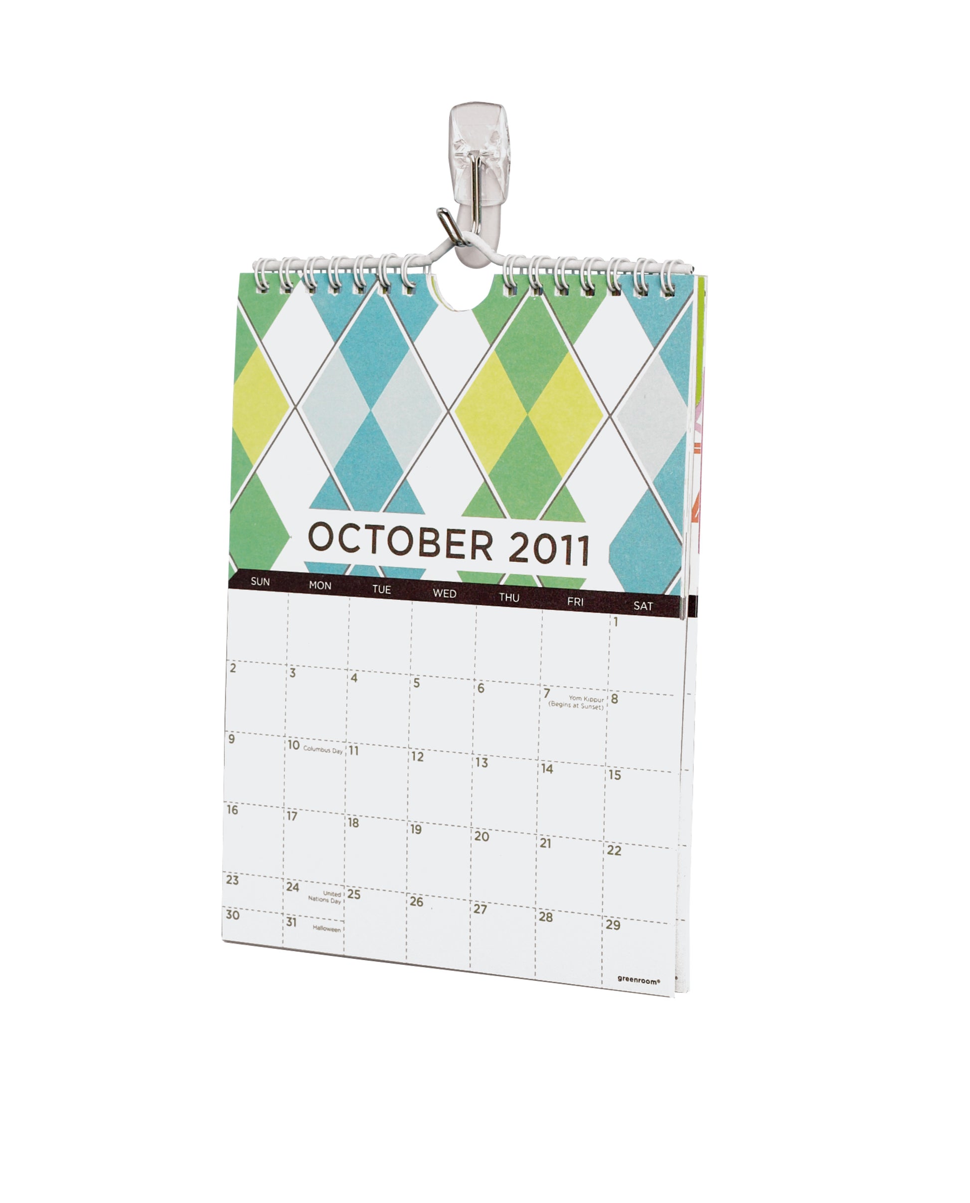 An einem weißen Wandhaken hängt ein kleiner, spiralgebundener Wandkalender bis Oktober 2011 mit buntem Rautenmuster: der Command™ Drahthaken, klein, transparent, mit transparenten Strips von 3M Deutschland GmbH.