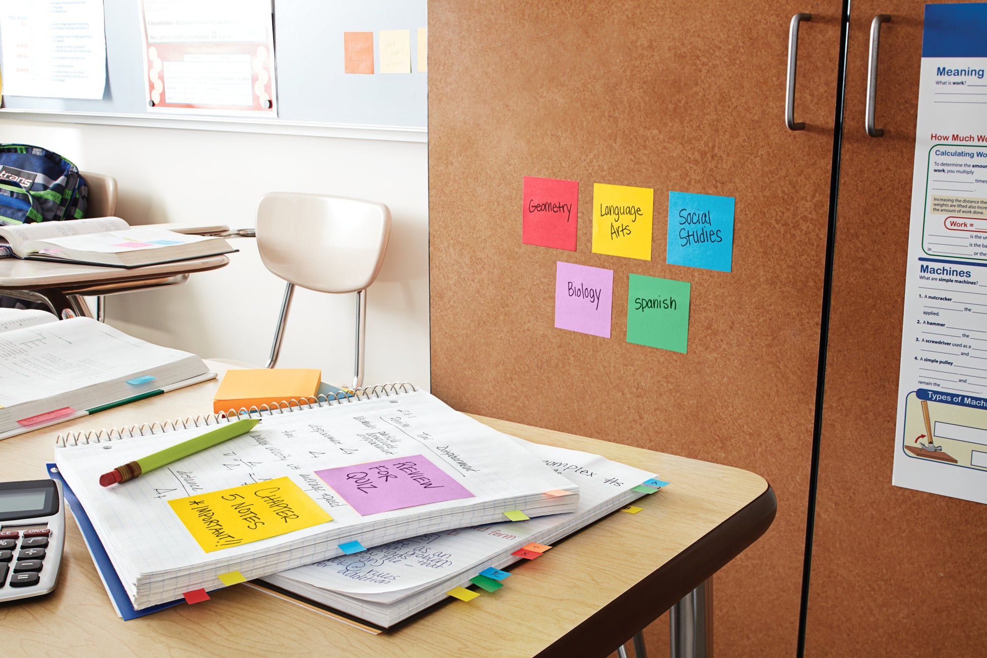 Ein Klassenzimmer mit aufgeschlagenen Heften, einem Taschenrechner und Schulbüchern ist mit dem 3M Deutschland GmbH Post-it® Z-Notes Dispenser, Bear, White und Super Sticky Z-Notes (Blue) ausgestattet, die Fächer wie Geometrie und Naturwissenschaften beschriften; auch leere Stühle sind zu sehen.