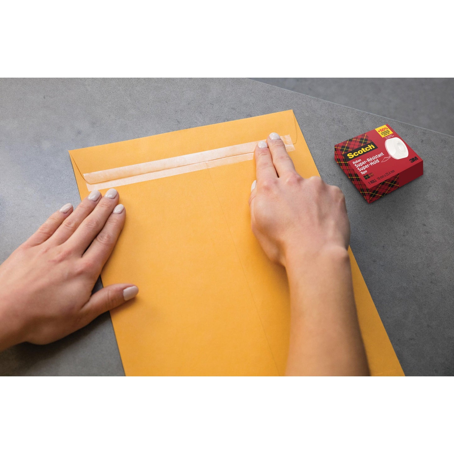 Eine Person verschließt einen großen braunen Umschlag mit Scotch® Super-Hold Secure Tape, 1 Rolle, 19 mm x 25,4 m von 3M Deutschland GmbH auf einer grauen Fläche. Der Karton des Klebebandes ist in der Nähe und gewährleistet eine starke und transparente Verklebung für einen sicheren Postversand.