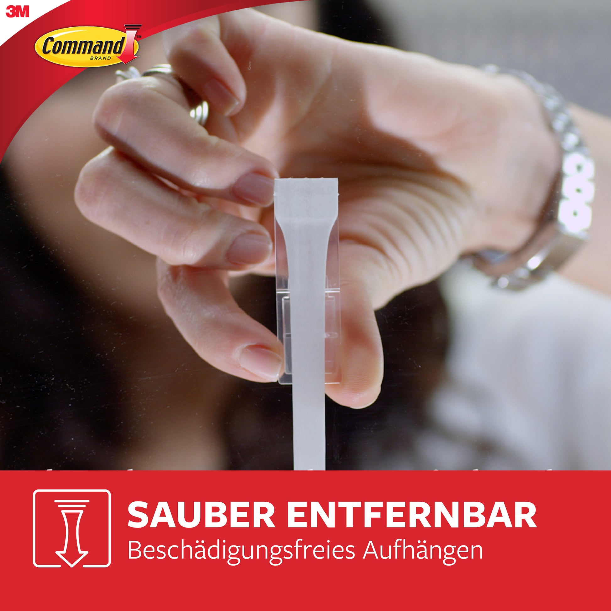 Eine Hand zieht einen weißen Streifen aus einem durchsichtigen Wandhaken, der das Logo der 3M Deutschland GmbH und einen deutschen Text zeigt, der die beschädigungsfreie Entfernung mit Multipack Command™ Strips, 17200 | Packung (1 Stück), hervorhebt.