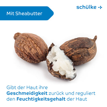The image shows three shea nuts, one of which is cut open to reveal the white shea butter inside. The German text in the upper left reads: "With shea butter." Below, the headline states: "Restores the skin's suppleness and regulates its moisture content. Dye and fragrance-free for intensive care. Schülke sensiva® dry skin balm by Schülke & Mayr GmbH."